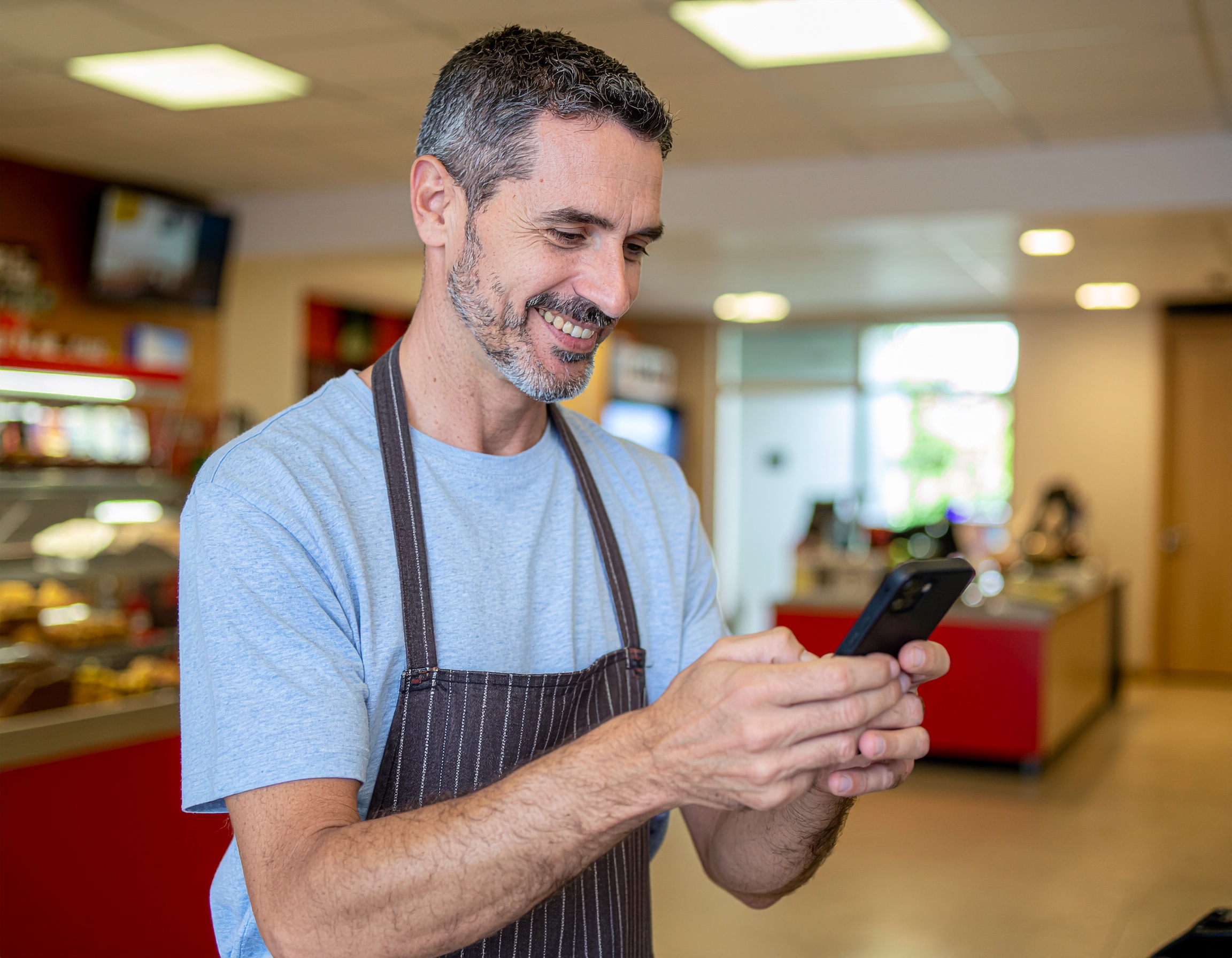 Happy store owner using Hubii on his phone